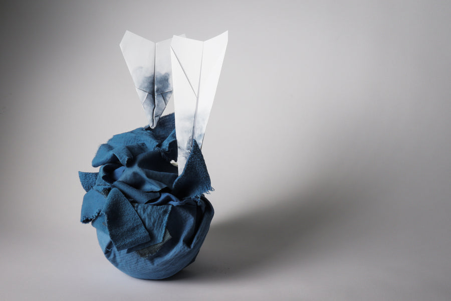 paper airplanes crashing into indigo-dyed fabric